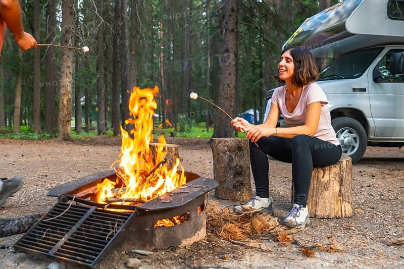 Tourists are roasting marshmallows over a campfire near their campervan in banff national park, canadian rockies, alberta, enjoying a relaxing evening in nature
