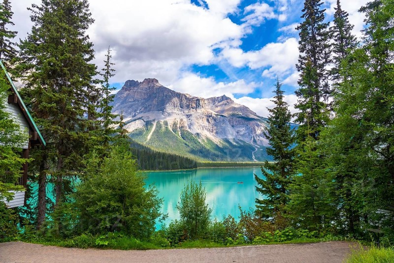 Emerald lake reflecting the majestic mount burgess under a cloudy sky, surrounded by lush vegetation and a wooden cabin in banff national park, alberta