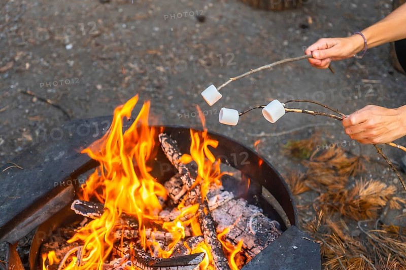 Tourists are roasting marshmallows over a campfire in banff national park, alberta, enjoying a relaxing evening in the canadian rockies near their campervan