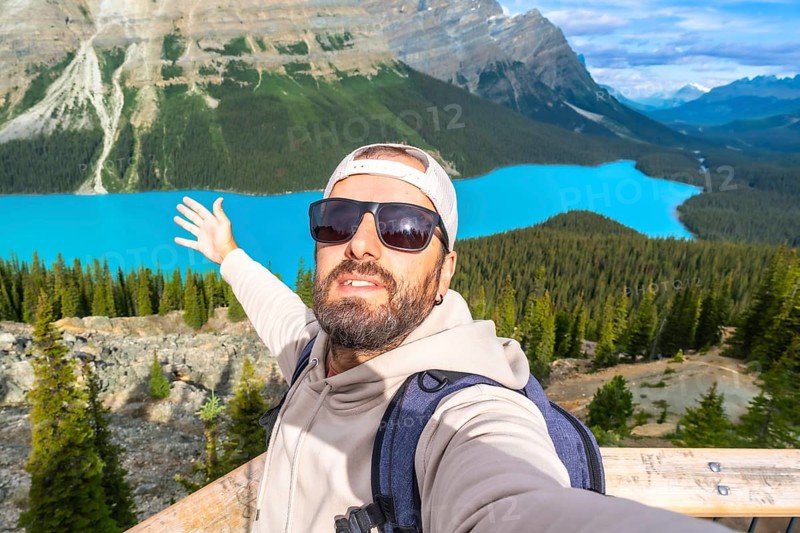 Tourist with a backpack and sunglasses taking a selfie at the scenic viewpoint of peyto lake in banff national park, enjoying the stunning turquoise waters and mountains