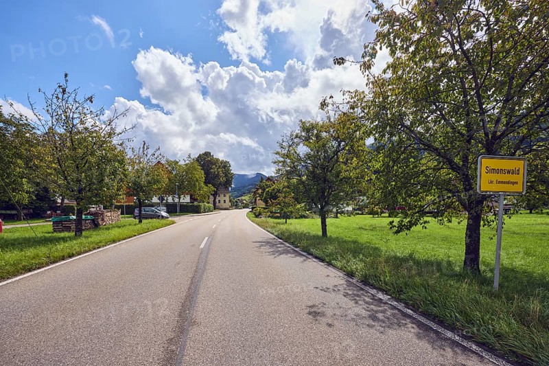 Landscape, town entrance sign, road, houses, trees with autumn leaves, hills, coniferous forest, meadow, sunlight, sunny, cloudy, blue sky, cumulus clouds, stratocumulus clouds, road An der Niederbruck, Simonswald, Black Forest, Emmendingen district, Baden-Württemberg, Germany