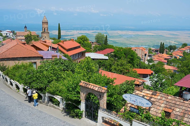 View of a paved street with lush vegetation and city view, St. George Church, Sighnaghi, Signagi, Kakheti Province, Greater Caucasus, Georgia, Western Asia
