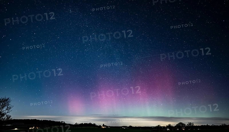 Glowing polar lights in shades of purple and green under a clear starry sky, EXPO Observatory Melle, Lower Saxony, Germany