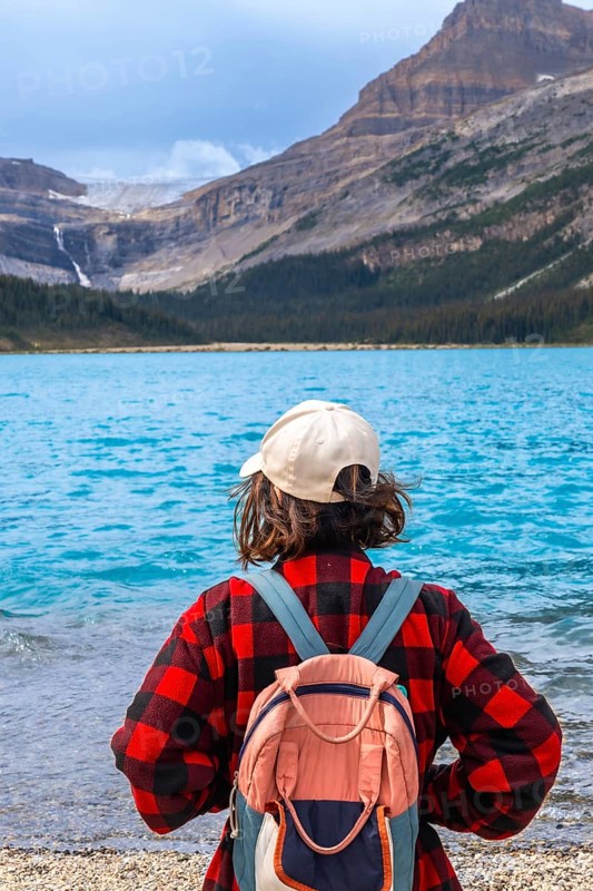 Female hiker with backpack enjoying breathtaking view of turquoise bow lake and crowfoot glacier in banff national park, canadian rockies, alberta, canada, promoting tourism and outdoor adventure
