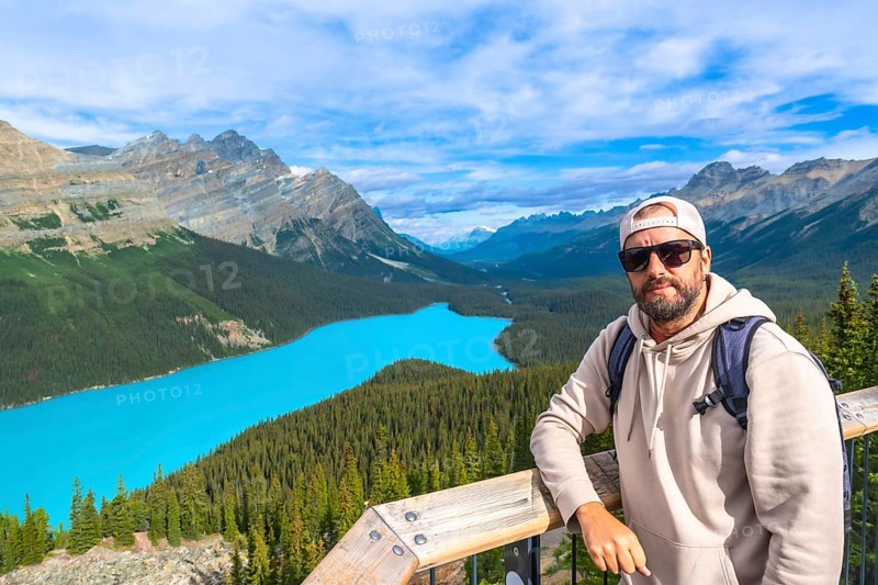 Backpacker standing on a scenic viewpoint, enjoying the stunning turquoise waters of peyto lake and the surrounding canadian rockies in banff national park, alberta, on a beautiful sunny day