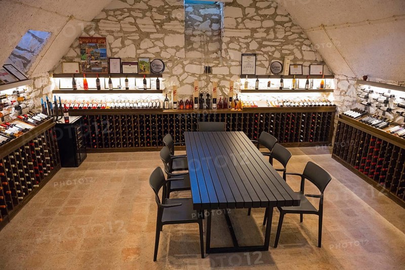 Wine cellar with long tasting table and chairs, surrounded by illuminated wine racks on stone walls, Georgian-German wine house from 1915, Bolnissi, Katharinenfeld, founded by Caucasian German settlers, Lower Kartli region, Kwemo Kartli, Georgia