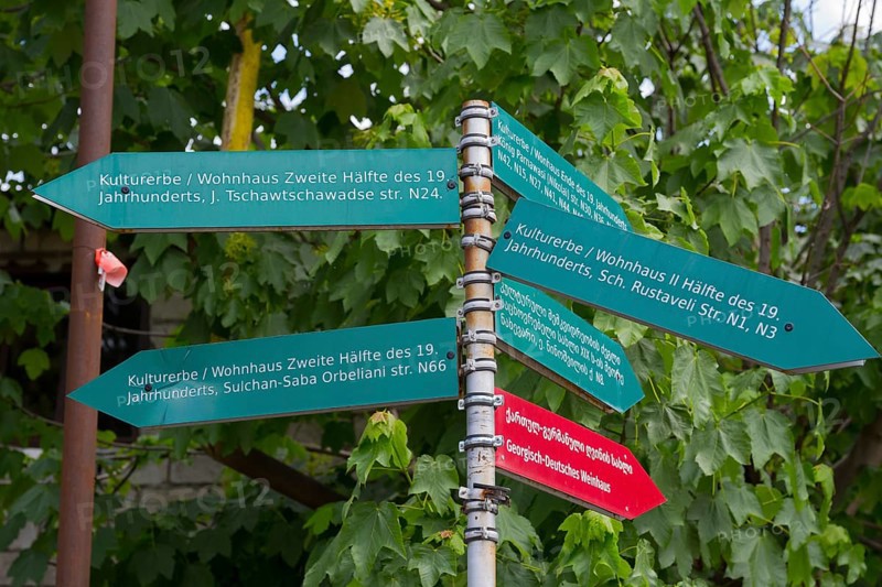 Green signpost with signs showing the cultural heritage of the 19th century under trees, Bolnissi, Katharinenfeld, founded by Caucasian German settlers, Lower Kartli region, Kwemo Kartli, Georgia