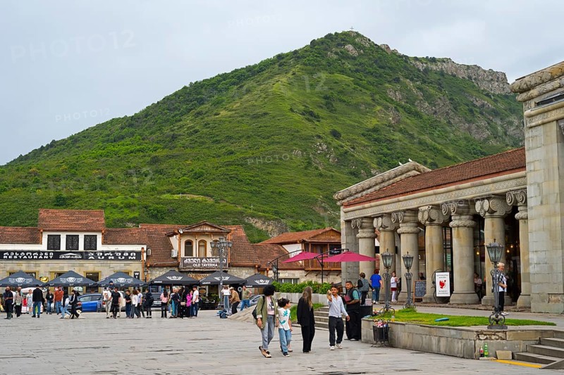 People gather in a square in front of historic buildings and a green mountain backdrop, Mtskheta Square, Mtskheta, Mtskheta, Mtskheta-Mtianeti region, Georgia