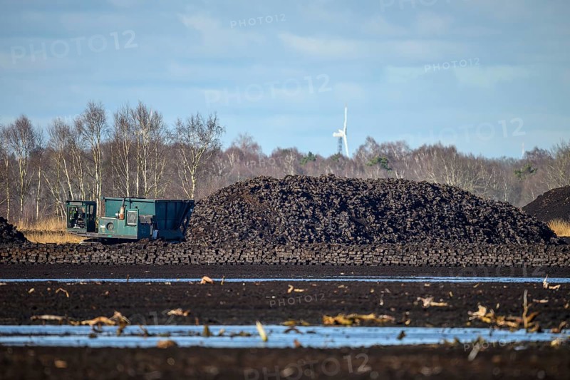 Layered peat sod Peeling of a high-moor black peat in cloudy skies with earthy colors and natural texture. On the left, a special vehicle for torfcutting peat mining, Diepholzer Moorniederung, Drebber, Lower Saxony, Germany