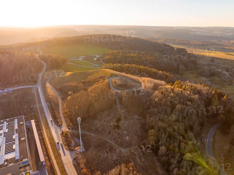 Aerial view of hilly landscape and forest in evening light, future PV building on old deposit, Lindenrain industrial park, Calw, Germany