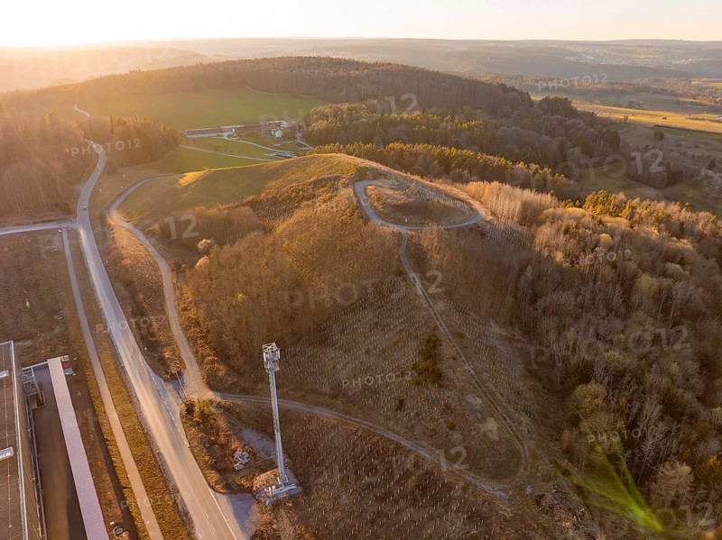 Hilly landscape with forest and roads in the warm light of sunset, future PV building on old deposit, Lindenrain industrial park, Calw, Germany