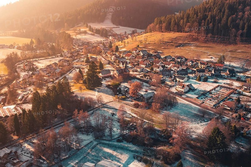 Expansive view of a village with snow-covered roofs surrounded by hills and forests, Enzklösterle, Calw district, Germany