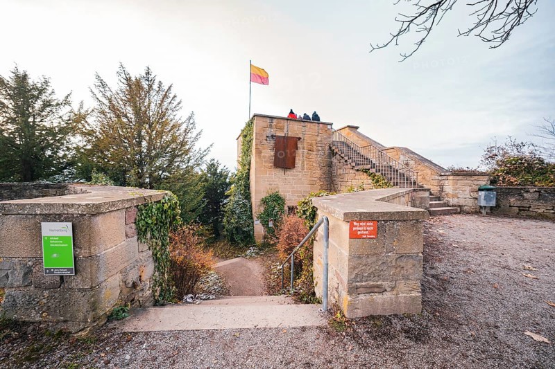 A historic castle wall with a waving flag and people enjoying the autumn view, Herrenberg, Böblingen district, Germany