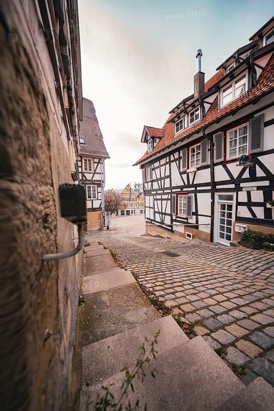 View through a narrow cobblestone alley in a historic old town, Herrenberg, Böblingen district, Germany