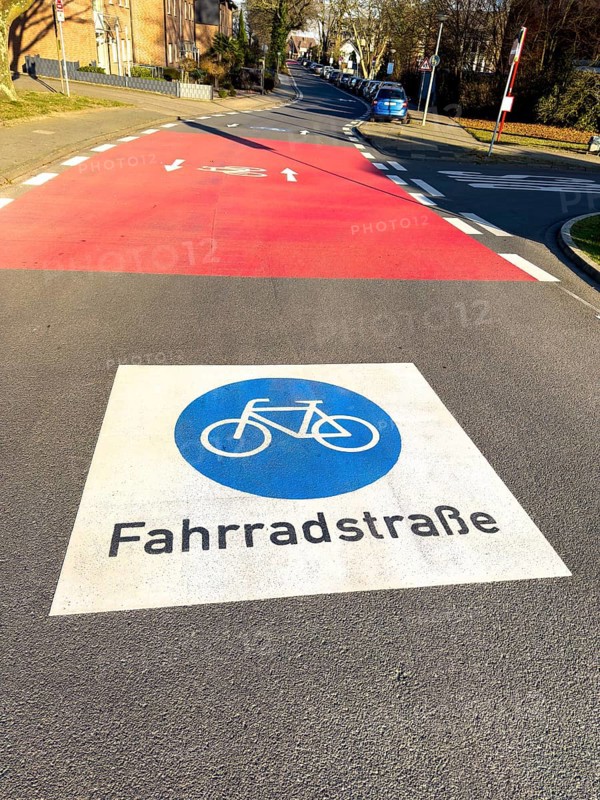 Large marking on road painted symbol for road signs 244.1-40 Start end of a bicycle road, behind it red intersection road confluence, Germany