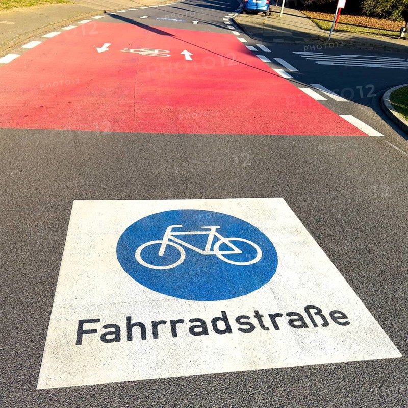 Large marking on road painted symbol for road signs 244.1-40 Start end of a bicycle road, behind it red intersection road confluence, Germany