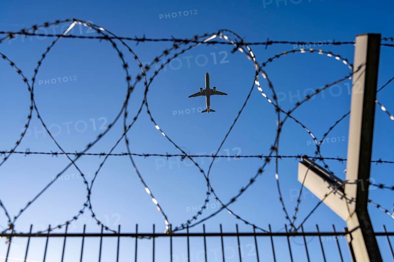 Symbolic picture security at the airport, outer fence at Düsseldorf International Airport, steel wire fence, with S-wire rollers, NATO wire, on the fence crown, airplane taking off, North Rhine-Westphalia, Germany
