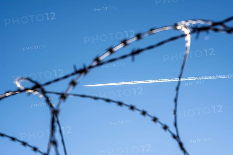 Symbolic picture security at the airport, outer fence at Düsseldorf International Airport, steel wire fence, with S-wire rollers, NATO wire, on the fence crown, airplane with wire strips at high altitude, North Rhine-Westphalia, Germany