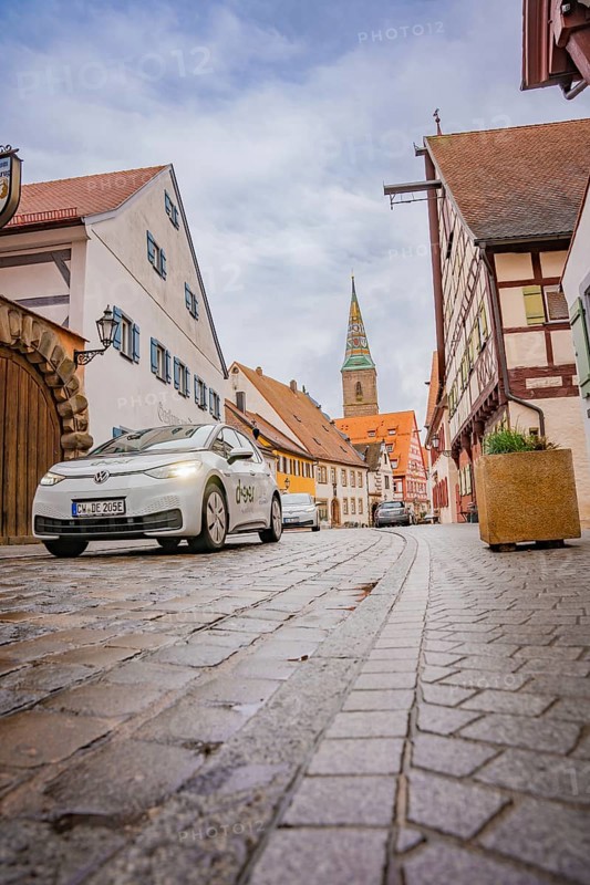 Electric car drives through a cobblestone old town with church tower, ID3, deer e-car sharing, Germany