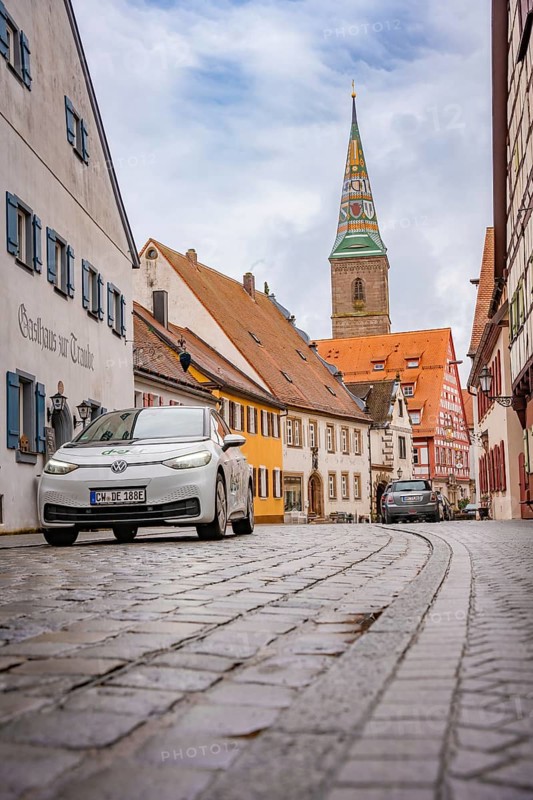 Paved alley in charming old town district with church tower, ID3, deer e-car sharing, Germany