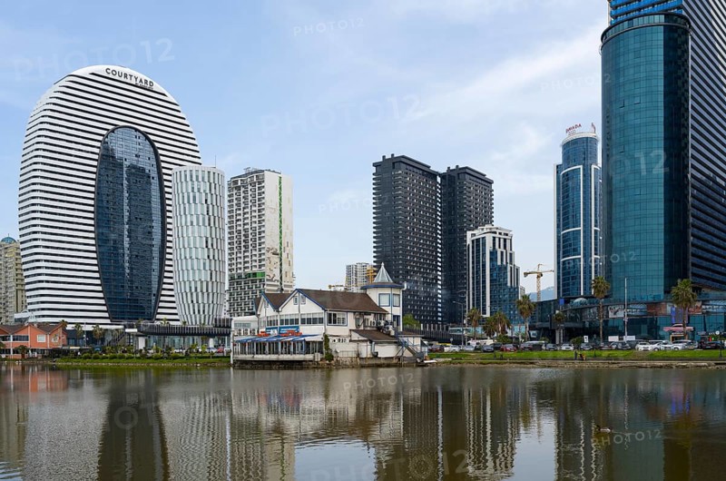 Modern high-rise buildings with glass facades are reflected in a calm lake under a cloudy sky, Batumi, Black Sea, Ajara region, Adjara, Autonomous Republic, Georgia