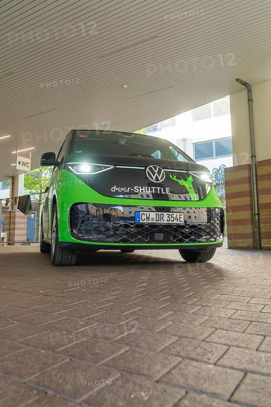 Green VW from the front in an urban, modern environment, Deer E-Mobility Shuttle Service, Calw, Germany