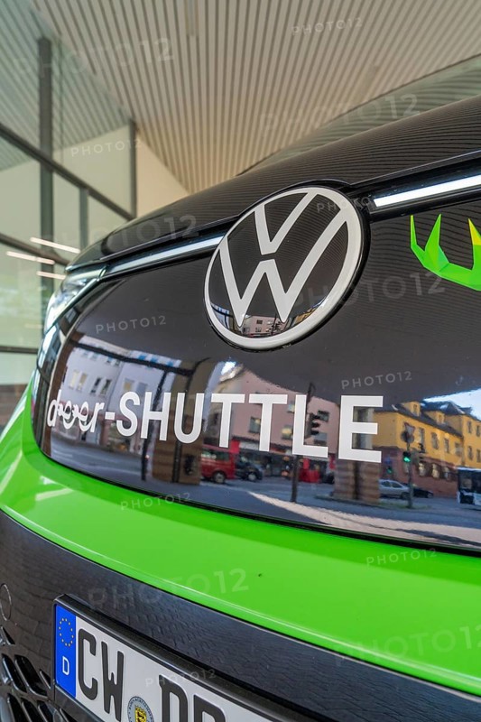 Front view of a green VW with sign in an urban environment, Deer E-Mobility Shuttle Service, Calw, Germany