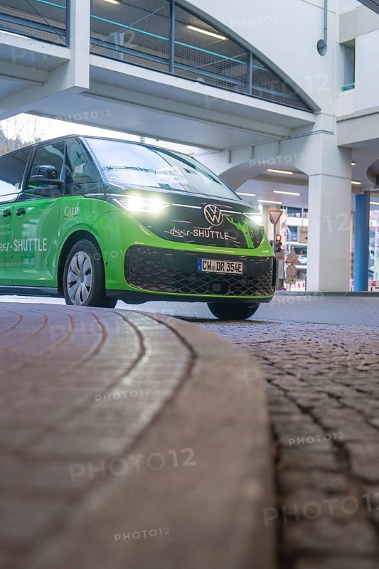 Green Volkswagen shuttle in front of a modern building in an urban area, Deer E-Mobility Shuttle Service, Calw, Germany