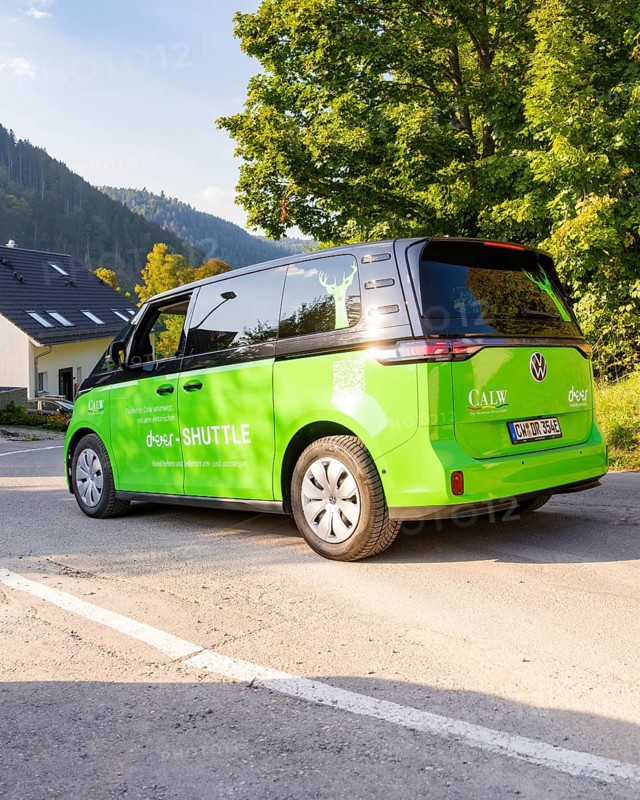Green car on road in picturesque landscape with mountains in the background, Deer E-Mobility Shuttle Service, Calw, Germany
