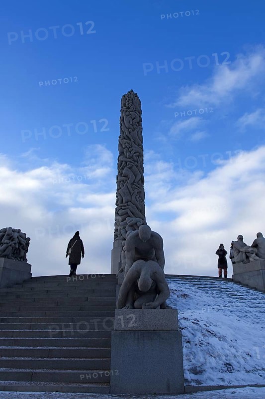 Monolith and sculptures on snowy stairs. People standing and admiring, Vigeland Sculpture Park Oslo Norway