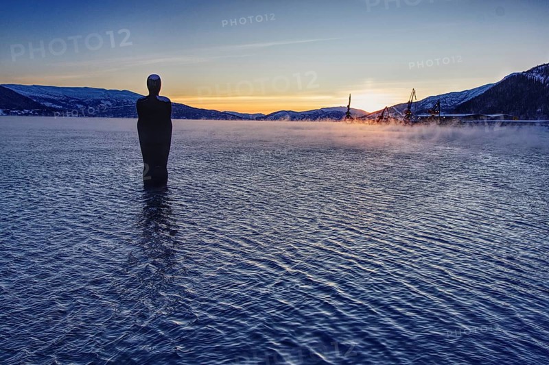 Sunset over a lake with a statue (Havmannen) in the water, Mo i Rana, Norway