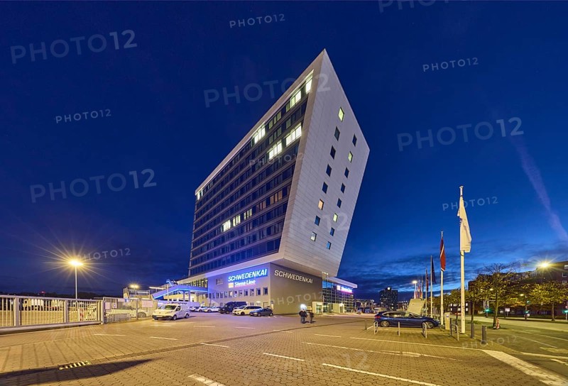 Schwedenkai ferry terminal, commercial buildings, modern architecture, vehicles, parking boxes, advertising flags on flagpoles, lantern, trees, evening blue hour, deep blue evening sky, cumulus clouds, Kaistraße, Kiel, state capital, district-free city, Schleswig-Holstein, Germany