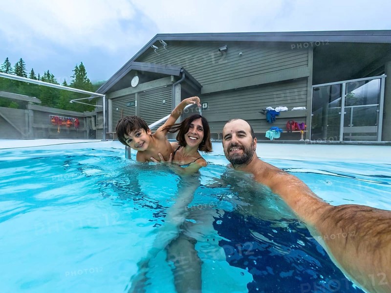 Happy family taking a selfie while bathing in miette hot springs, the hottest natural hot springs in the canadian rockies, located in jasper national park, alberta, canada