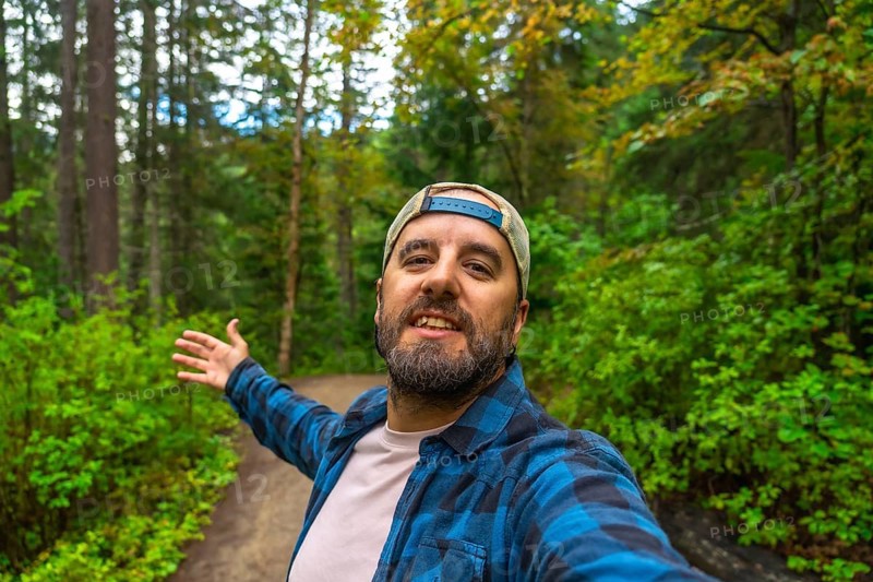 Happy hiker taking a selfie with open arms while walking the overlander falls trail in mount robson provincial park, british columbia, canada, surrounded by lush green forest