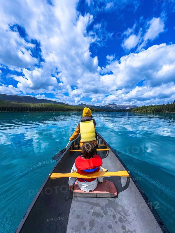 Tourists paddling a canoe on beautiful maligne lake in jasper national park, alberta, canada, enjoying a sunny day surrounded by stunning nature