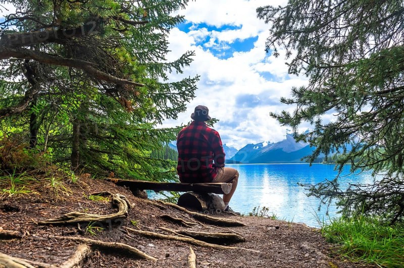 Tourist is enjoying the breathtaking view of turquoise maligne lake and its surrounding mountains in jasper national park, a renowned unesco world heritage site in the canadian rockies
