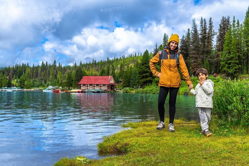 Mother and son holding hands, enjoying a scenic view of maligne lake boathouse in jasper national park, alberta, canada, surrounded by pristine nature and a tranquil atmosphere