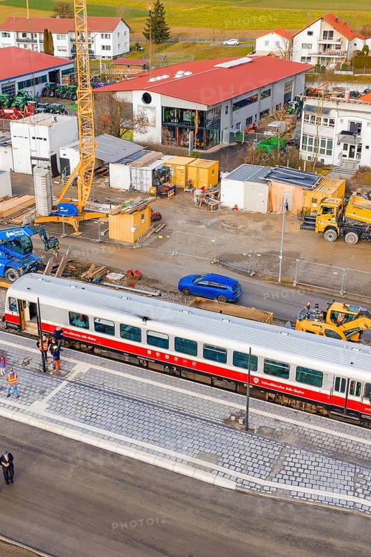 A train on a platform in the middle of a construction site with construction site vehicles and surrounding buildings, historic event, first test run with a passenger train on the Hermann tracks, Hesse Railway since 1988, Calw district, Germany