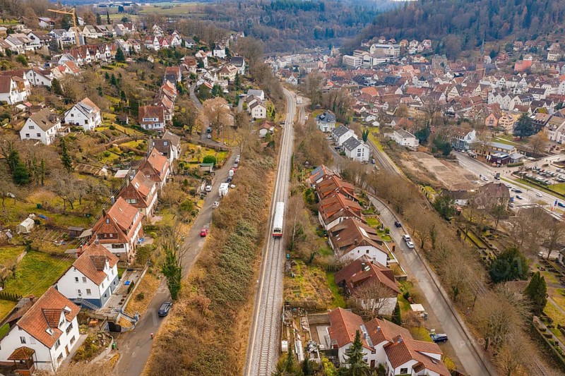 A train travels through a residential area that stretches along a wooded hill, historic event, first test run with a passenger train on the Hermann tracks, Hesse Railway since 1988, Calw, Calw district, Germany