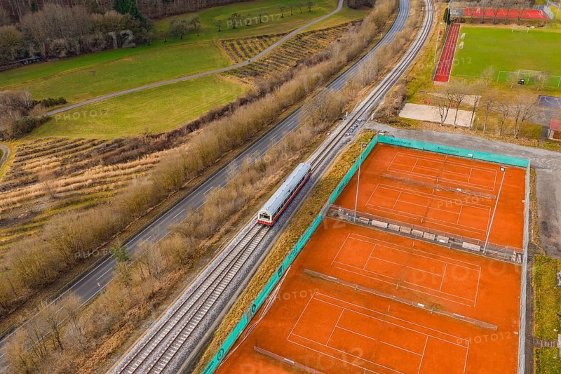 A train travels through rural surroundings next to several tennis courts and fields, historic event, first test run with a passenger train on the Hermann tracks, Hesse railway since 1988, Ostelsheim, Calw district, Germany