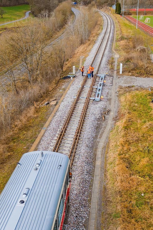 View along the railway tracks with a train and several construction workers on the rails, historic event, first test run with a passenger train on the Hermann tracks, Hesse Railway since 1988, Calw district, Germany
