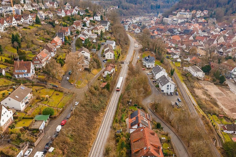 City with close-standing houses along a railway line through hilly, wooded landscape, historic event, first test run with a passenger train on the Hermann tracks, Hesse Railway since 1988, Calw, Calw district, Germany