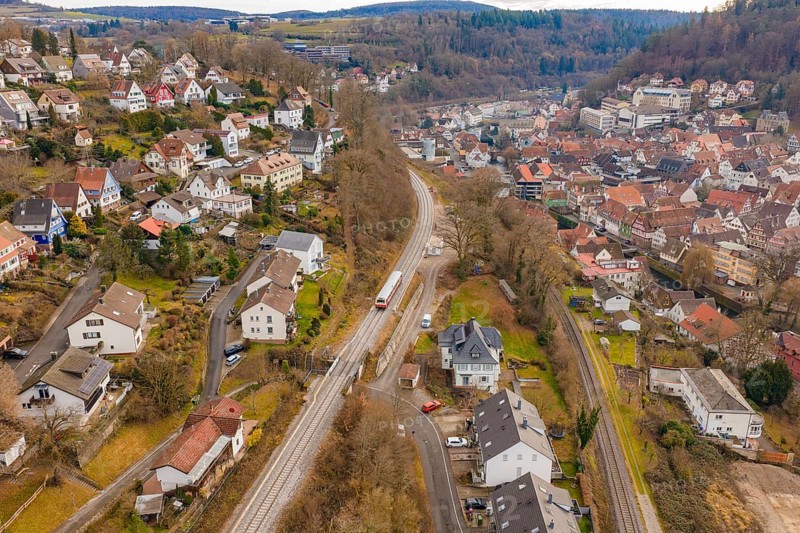 Urban landscape with railway line through hills with various houses and trees, historic event, first test run with a passenger train on the Hermann tracks, Hesse Railway since 1988, Calw, Calw district, Germany