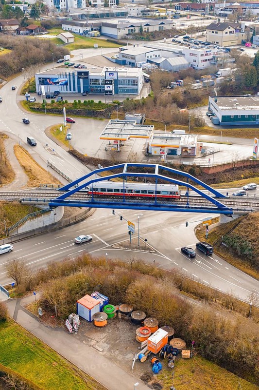 A train crosses a bridge over a roundabout in an urban environment, historic event, first test run with a passenger train on the Hermann tracks, Hesse Railway since 1988, Calw district, Germany