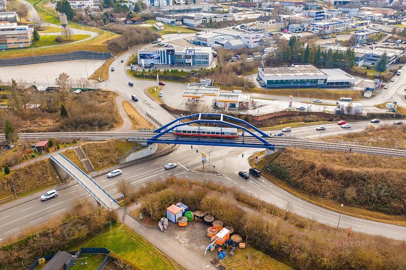 A train crosses a busy road junction in the city on a bridge, historical event, first test drive with a passenger train on the Hermann tracks, Hesse Railway since 1988, Calw, Heumaden, Calw district, Germany