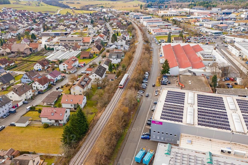 Train in a suburban landscape with residential buildings and industrial complexes, surrounded by rolling hills, historic event, first test run with a passenger train on the Hermann tracks, Hesse Railway since 1988, Althengstett, Calw district, Germany