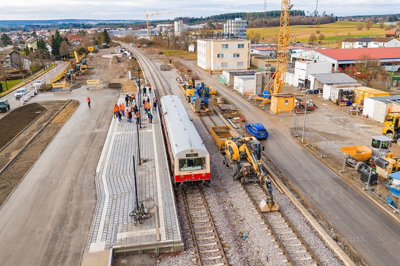Train surrounded by workers and cranes at construction site, industrial buildings and vehicles in the background, historic event, first test drive with a passenger train on the Hermann tracks, Hesse Railway since 1988, Althengstett, Calw district, Germany