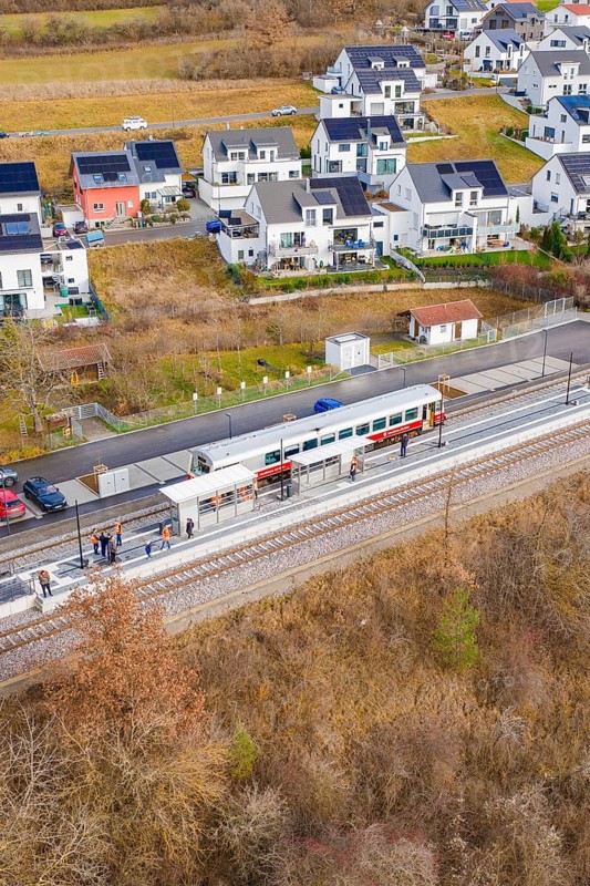 Train stops at a small train station next to modern houses surrounded by fields, historic event, first test run with a passenger train on the Hermann tracks, Hesse Railway since 1988, Ostelsheim, Calw district, Germany