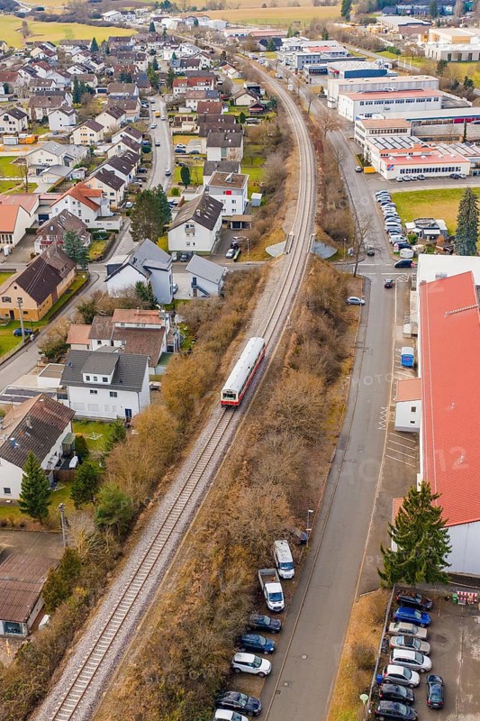 A train travels through an urban area along railroad tracks, past residential and industrial buildings, historic event, first test run with a passenger train on the Hermann tracks, Hesse Railway since 1988, Althengstett, Calw district, Germany