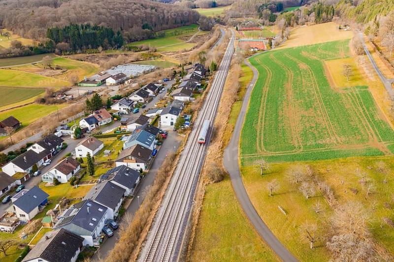 A train travels through a village, surrounded by fields and forests, along the railway tracks, historic event, first test run with a passenger train on the Hermann tracks, Hesse Railway since 1988, Ostelsheim, Calw district, Germany